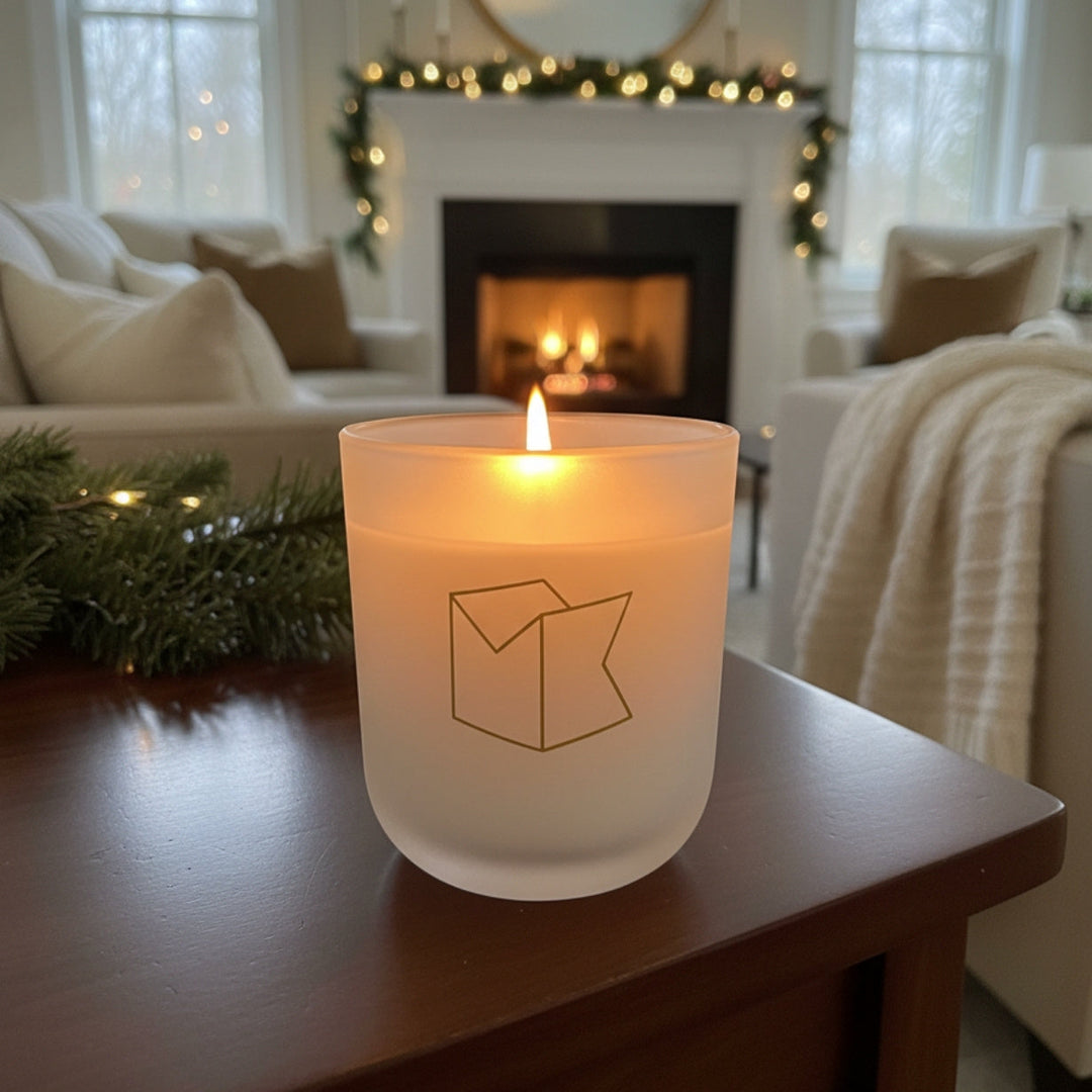 Michael Knowles's "Snowles" candle on a wooden table in a cozy living room.